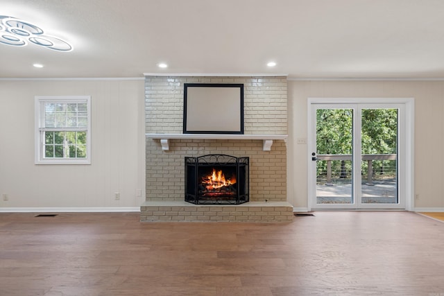 unfurnished living room with a wealth of natural light, crown molding, and wood finished floors