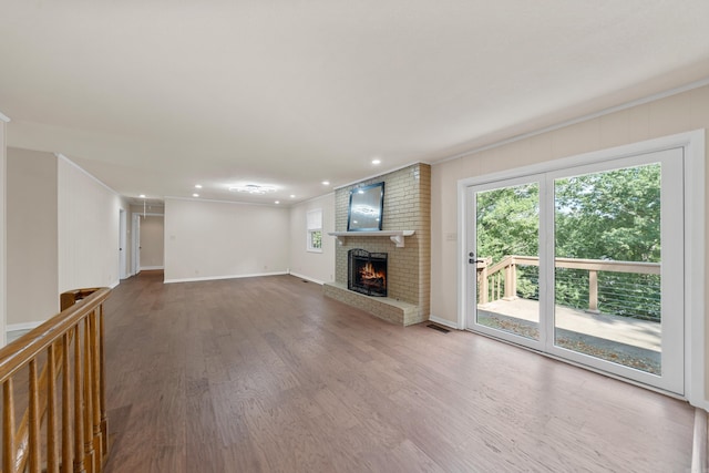 unfurnished living room featuring visible vents, baseboards, wood finished floors, a brick fireplace, and recessed lighting