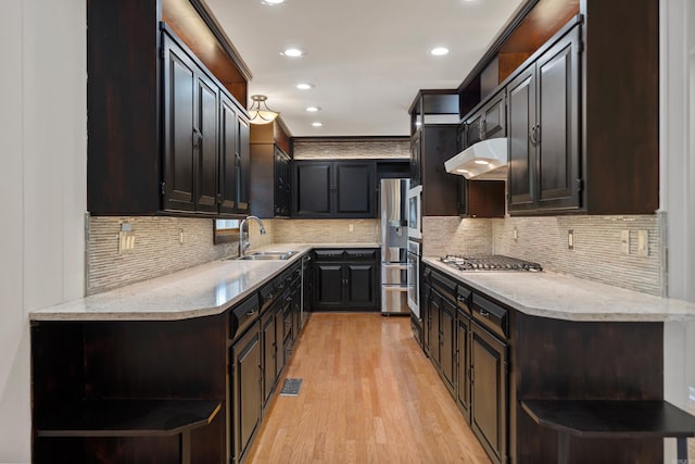 kitchen featuring stainless steel appliances, a sink, a peninsula, and open shelves