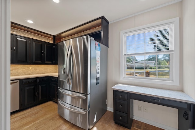 kitchen with stainless steel appliances, dark cabinetry, light wood-style floors, and built in study area