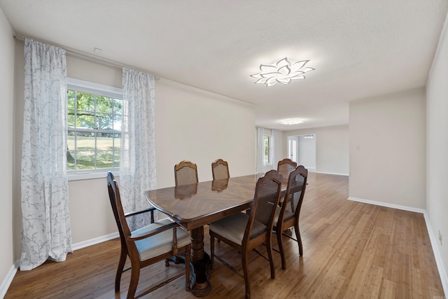 dining area with baseboards and wood finished floors