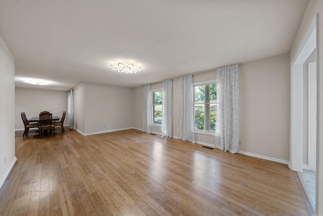 empty room featuring light wood finished floors, baseboards, and visible vents