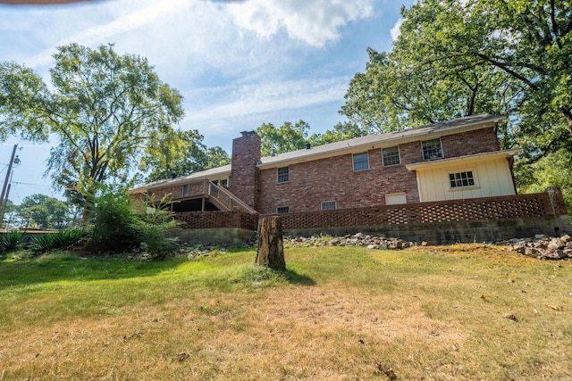 back of property with brick siding, a yard, and a chimney