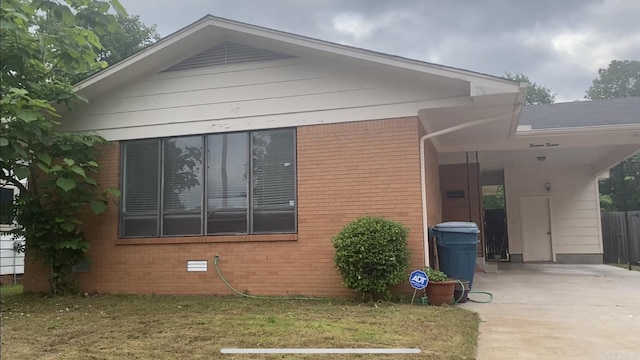 view of home's exterior with concrete driveway, a lawn, and brick siding