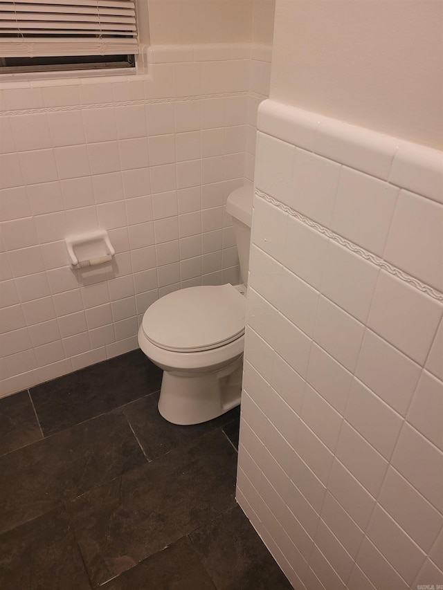 bathroom with wainscoting, tile walls, toilet, and tile patterned floors