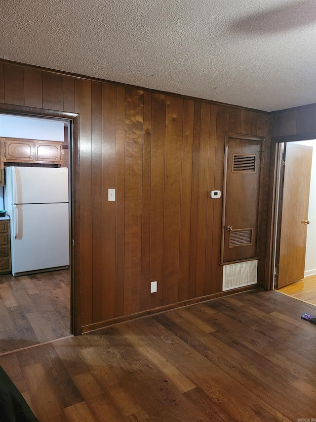 spare room featuring dark wood-style flooring, visible vents, and a textured ceiling