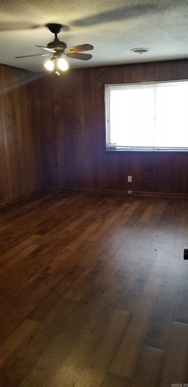 spare room featuring a ceiling fan, a textured ceiling, visible vents, and dark wood-type flooring