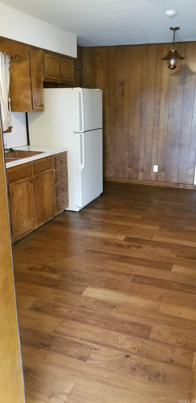 kitchen with light countertops, brown cabinetry, wood finished floors, and freestanding refrigerator