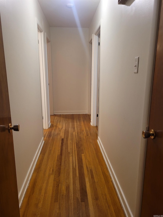 hallway featuring baseboards and wood finished floors