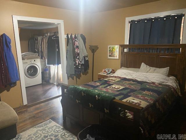 bedroom featuring dark wood-style floors and washer / dryer