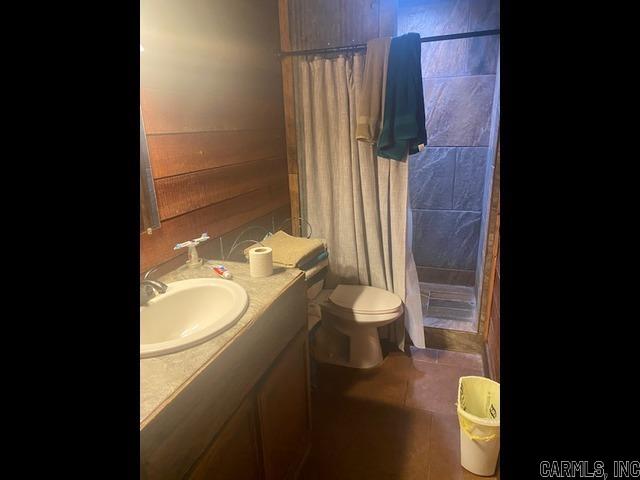 bathroom with toilet, curtained shower, tile patterned flooring, and vanity