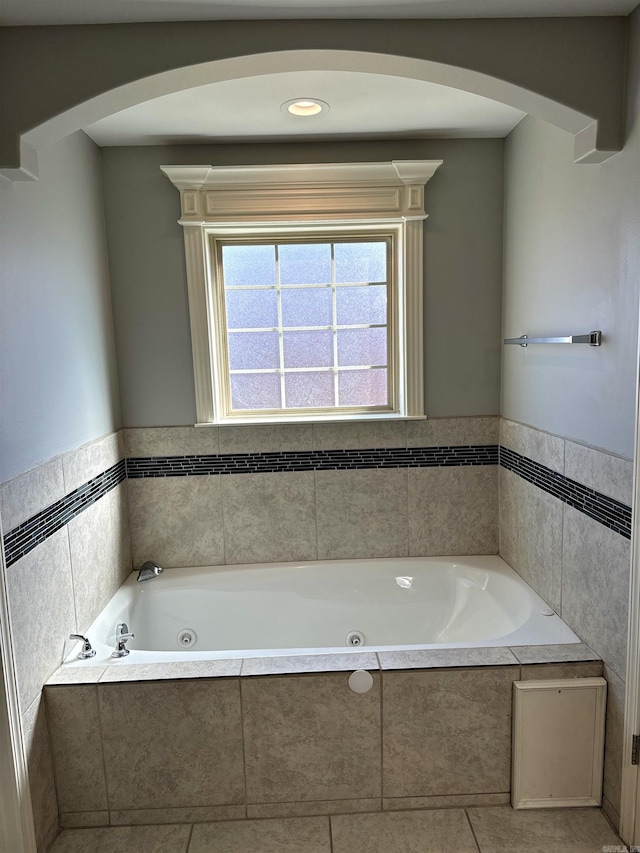 bathroom with a tub with jets, tile walls, and tile patterned floors