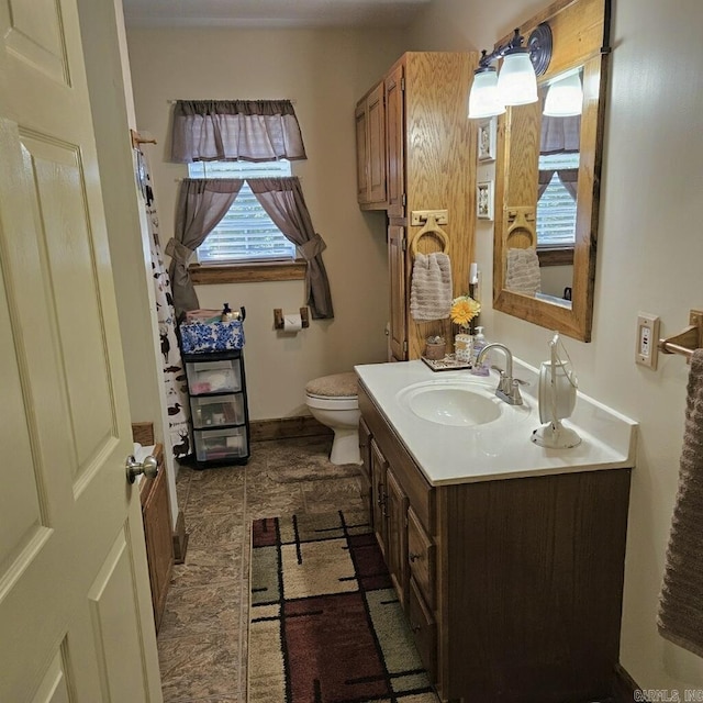 bathroom with toilet, baseboards, and vanity