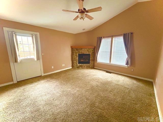 unfurnished living room with lofted ceiling, plenty of natural light, a fireplace, and carpet flooring