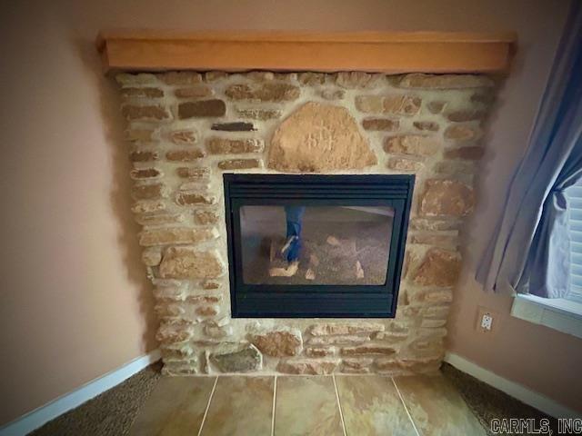 interior details featuring a stone fireplace and baseboards