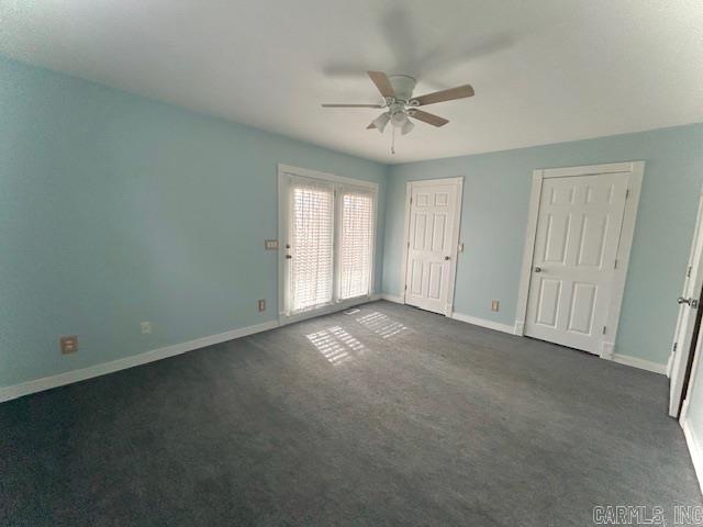 unfurnished bedroom with dark colored carpet, ceiling fan, and baseboards