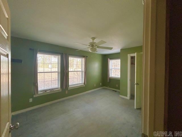 carpeted empty room with baseboards and a ceiling fan