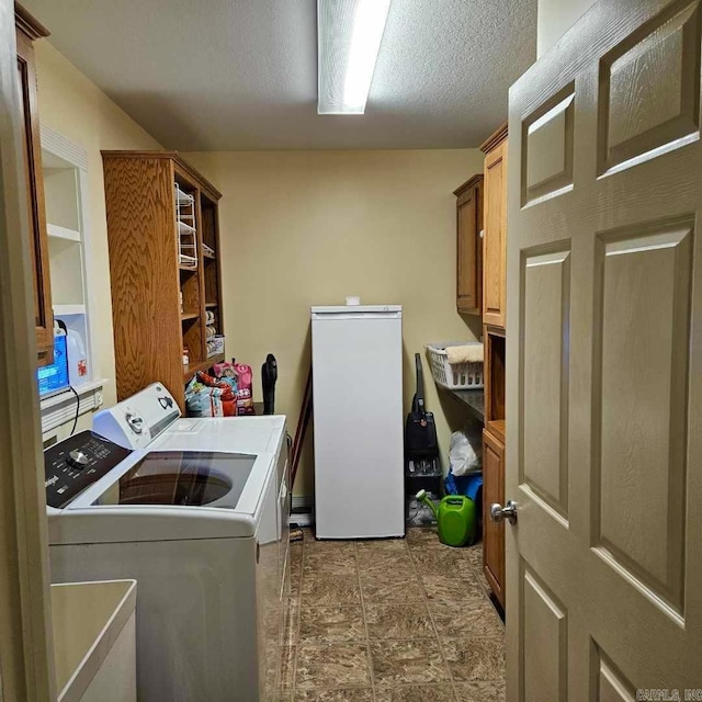 washroom with cabinet space, a textured ceiling, and washer and dryer