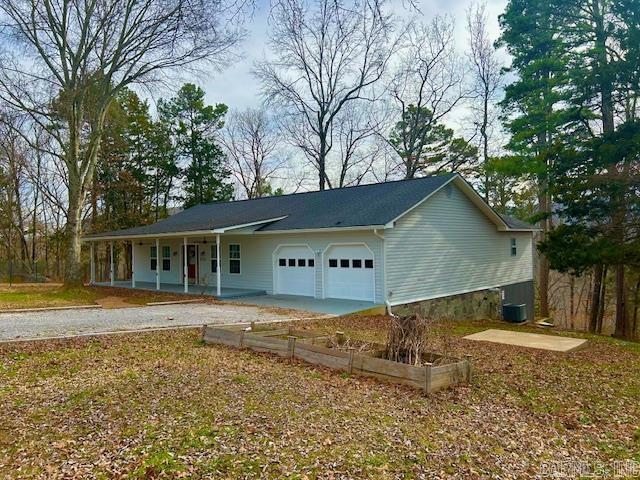 ranch-style house with covered porch, an attached garage, and central AC unit