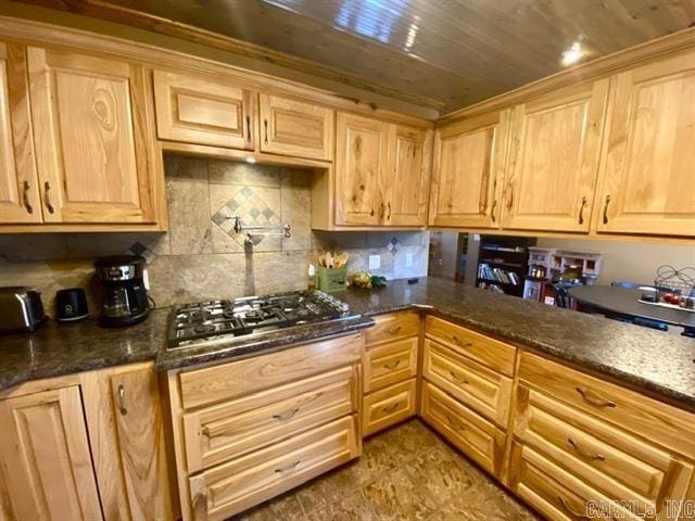 kitchen with wood ceiling, stainless steel gas cooktop, backsplash, and dark stone countertops