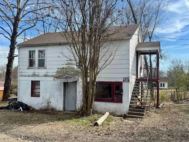 view of front of home with a shingled roof and stairs