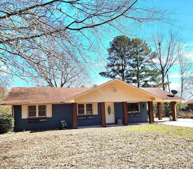 ranch-style house with a carport, brick siding, and concrete driveway