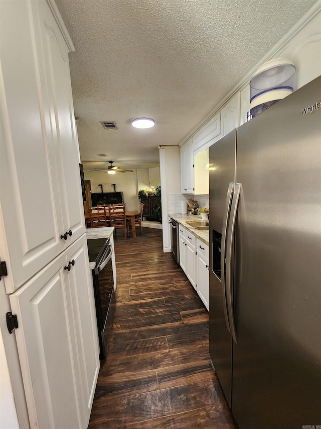 kitchen featuring dark wood-style floors, light countertops, appliances with stainless steel finishes, white cabinets, and a sink