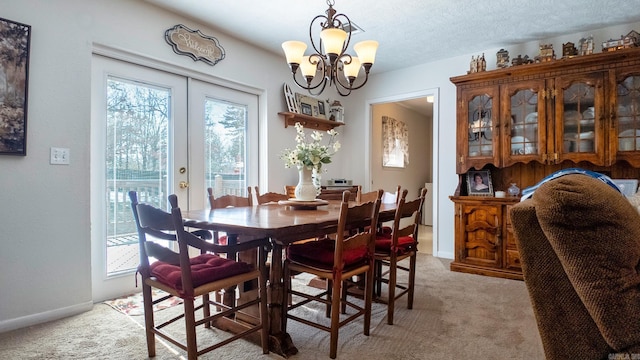 dining space featuring baseboards, light colored carpet, a textured ceiling, french doors, and a notable chandelier