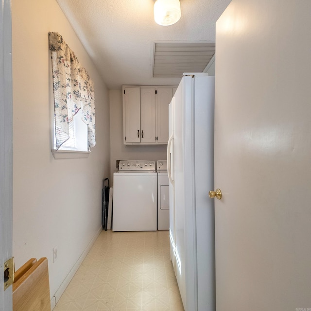 laundry area featuring cabinet space, baseboards, washer and dryer, a textured ceiling, and light floors