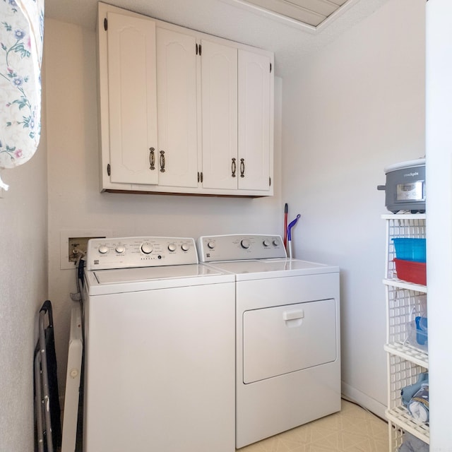 washroom featuring light floors, washer and clothes dryer, and cabinet space