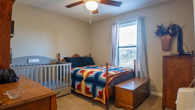 bedroom featuring a ceiling fan, light carpet, a textured ceiling, and baseboards