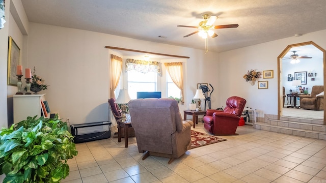 living area featuring light tile patterned floors, a textured ceiling, visible vents, and a ceiling fan