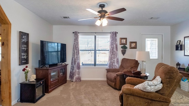 living room with ceiling fan, visible vents, a textured ceiling, and light colored carpet