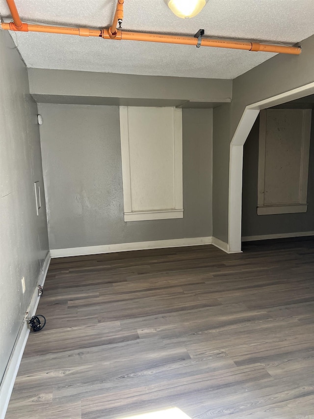 empty room featuring a textured ceiling, baseboards, and wood finished floors