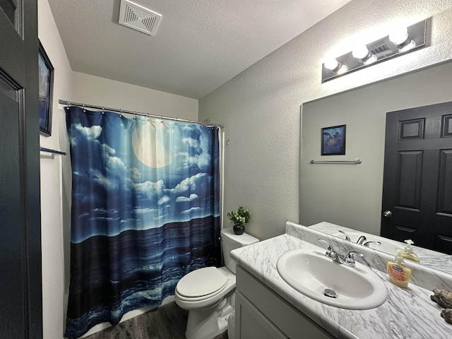 full bathroom with visible vents, a textured wall, wood finished floors, a textured ceiling, and vanity