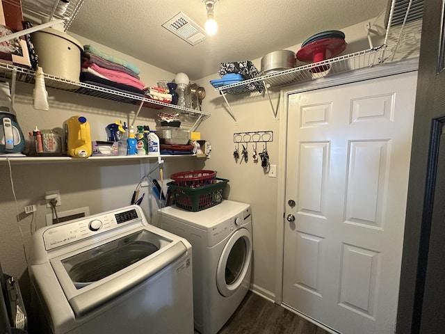 clothes washing area with laundry area, visible vents, washer and clothes dryer, dark wood-type flooring, and a textured ceiling