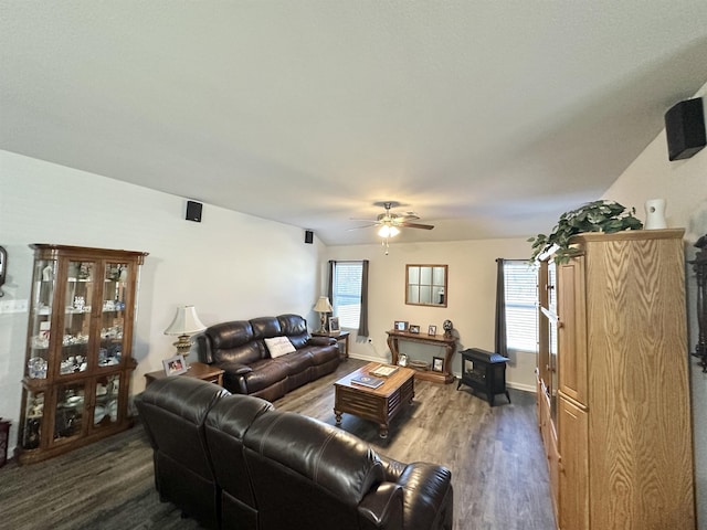 living room featuring a healthy amount of sunlight, ceiling fan, baseboards, and dark wood-type flooring