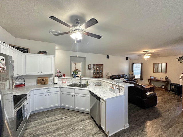 kitchen with appliances with stainless steel finishes, open floor plan, white cabinetry, a sink, and a peninsula