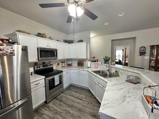 kitchen with stainless steel appliances, a peninsula, a sink, and white cabinets