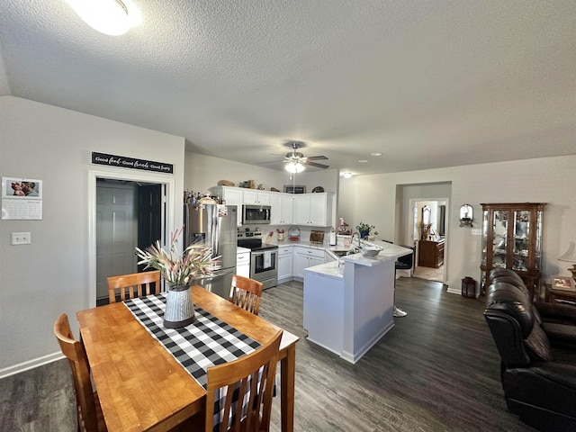 dining area with ceiling fan, a textured ceiling, baseboards, and dark wood-type flooring