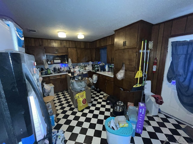 kitchen featuring light countertops, wood walls, a textured ceiling, and light floors