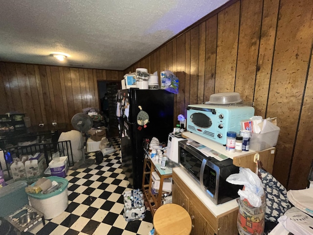 kitchen with light floors, light countertops, freestanding refrigerator, wood walls, and a peninsula