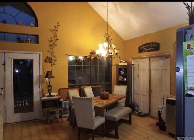 dining area featuring a notable chandelier, high vaulted ceiling, and wood finished floors