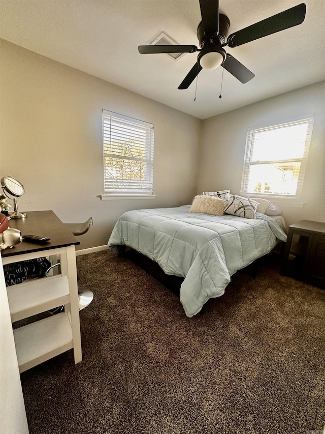 bedroom with ceiling fan, dark colored carpet, multiple windows, and baseboards