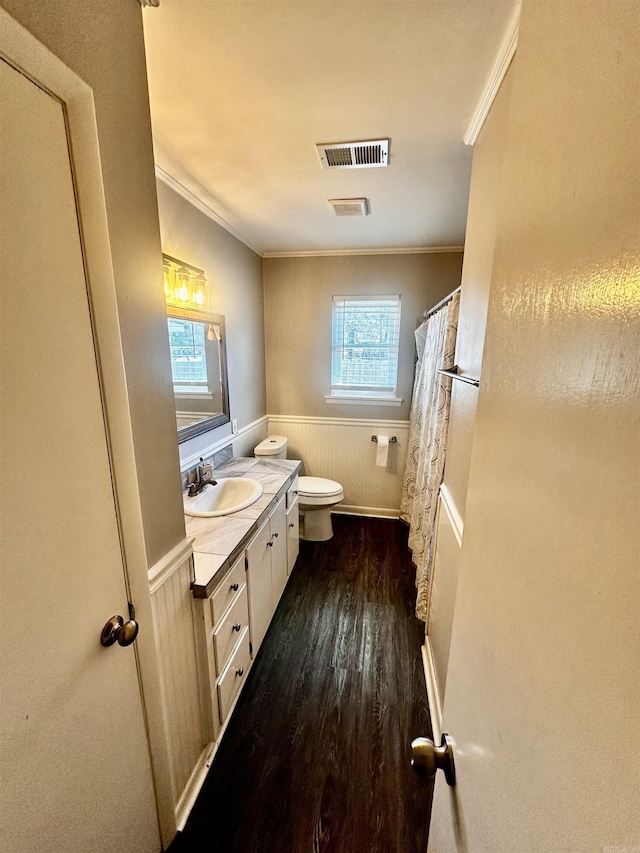 bathroom featuring a wainscoted wall, visible vents, ornamental molding, vanity, and wood finished floors