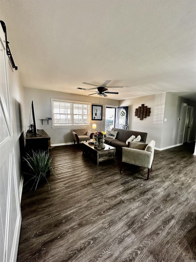 living room featuring dark wood-type flooring, a healthy amount of sunlight, ceiling fan, and baseboards