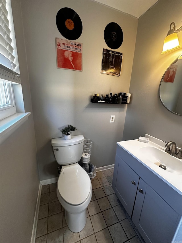 half bath featuring baseboards, vanity, toilet, and tile patterned floors