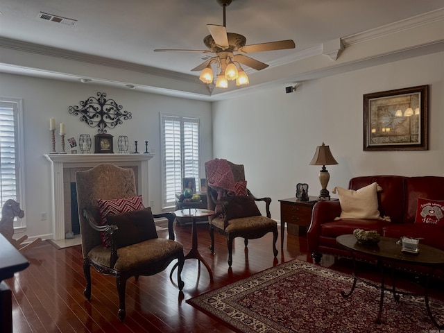 sitting room with ornamental molding, visible vents, ceiling fan, and wood finished floors