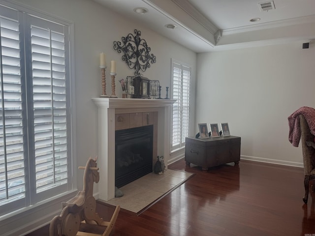 living area featuring a fireplace, visible vents, dark wood-type flooring, ornamental molding, and baseboards