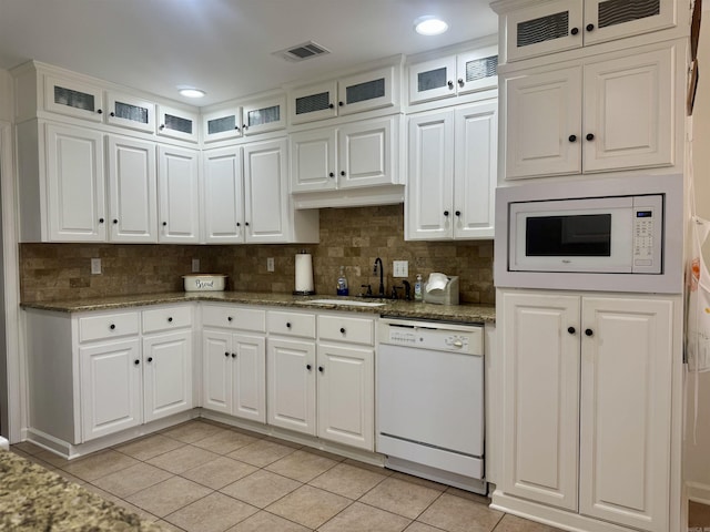 kitchen with light tile patterned floors, white appliances, a sink, white cabinets, and glass insert cabinets